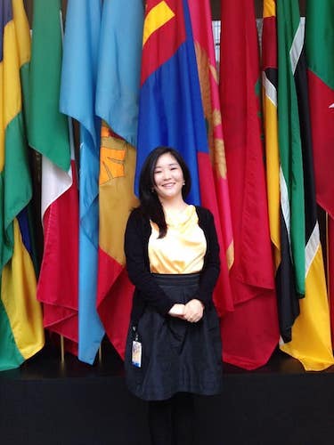 Batzul Dashdorj standing in front of a backdrop of flags