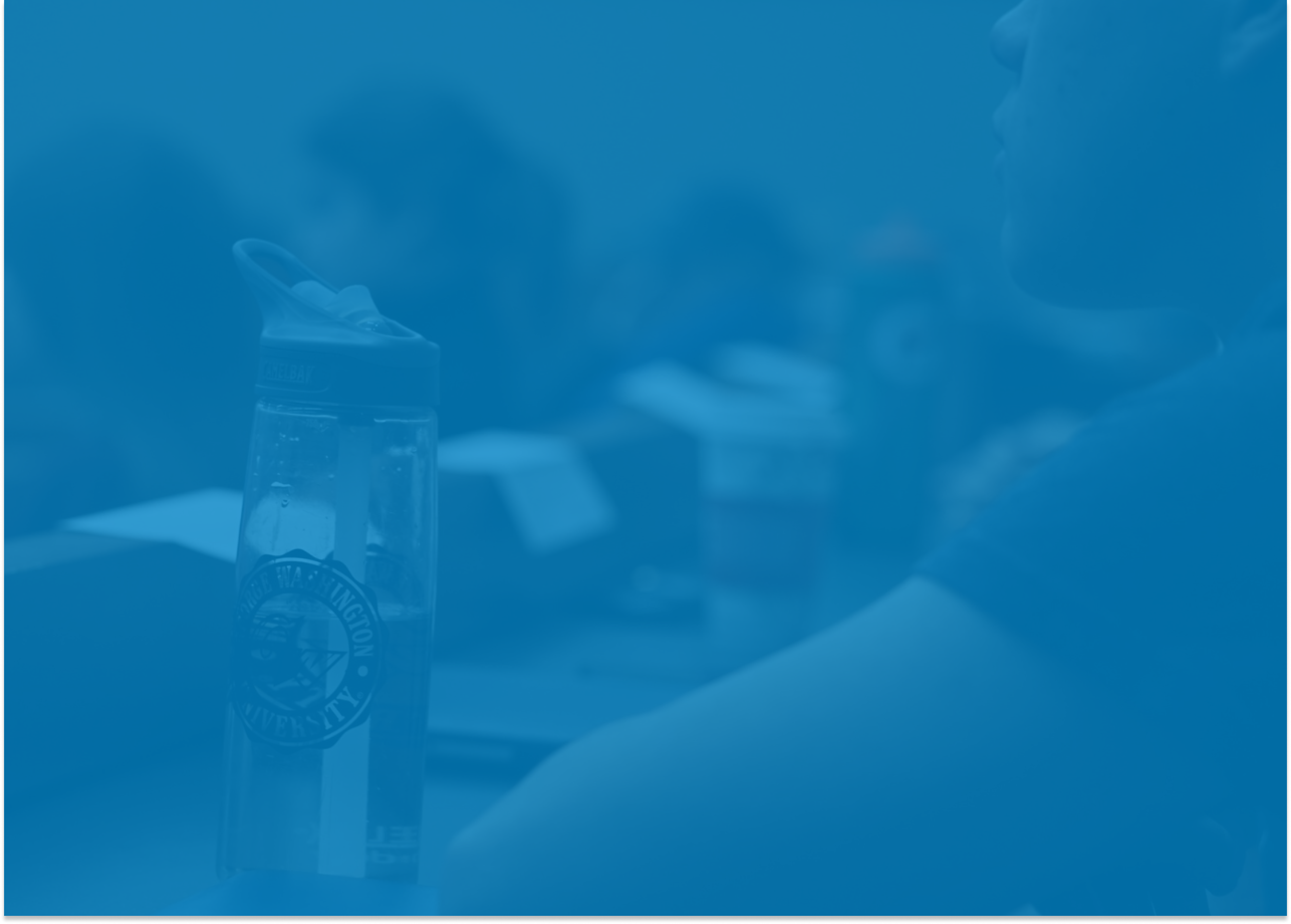 Close up shot of a male student looking to the front of a lecture hall with his water bottle to his left.