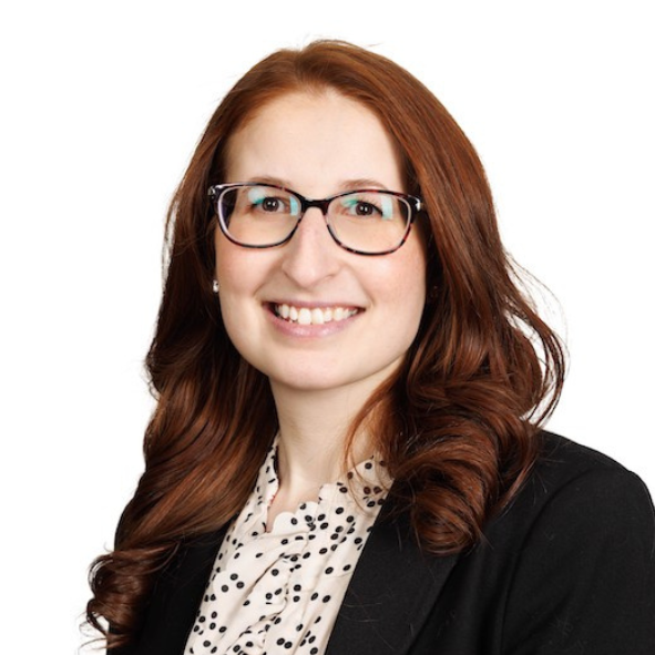 Danielle Goldstein smiles. She is wearing a glasses, a black blazer, and a white shirt.