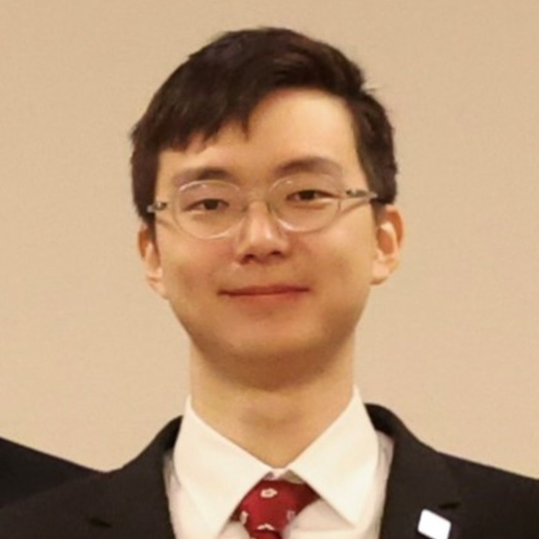 David Feng smiles, wearing a black blazer, white shirt, and red tie.