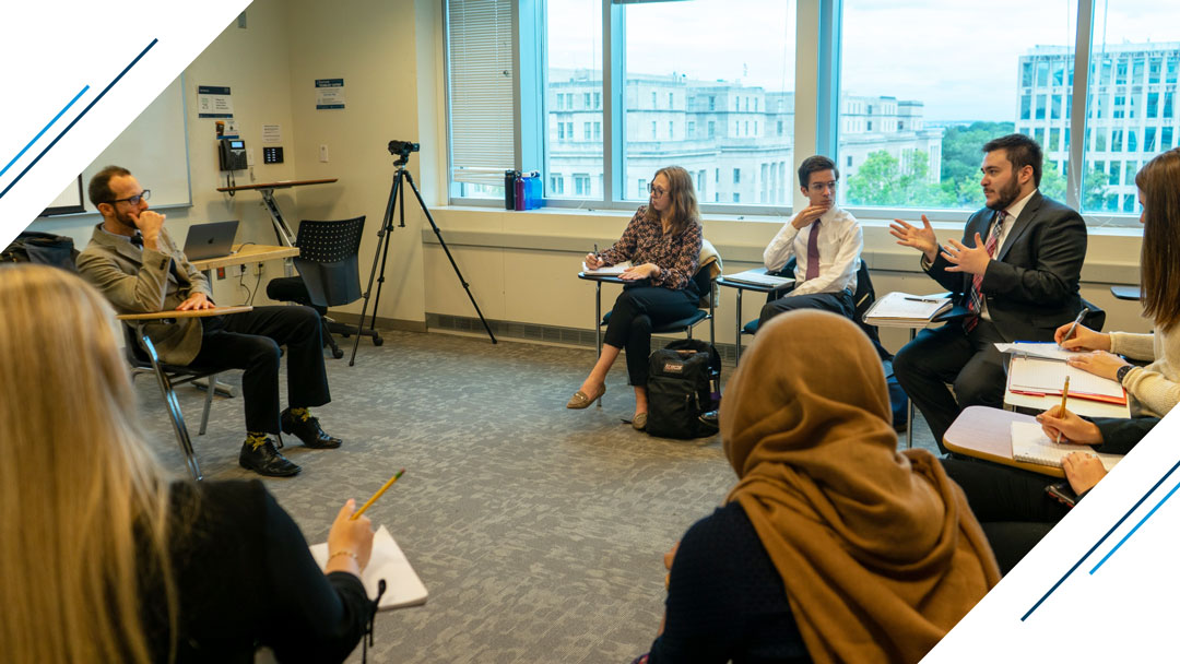 Deans Scholars class - professor and the rest of the class listens as a student answers a question