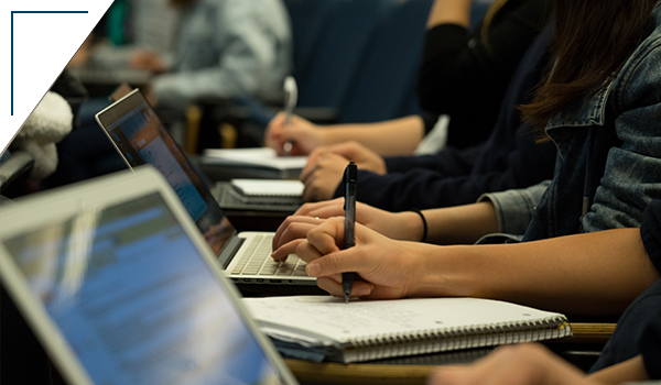 Photograph: students taking notes in class on their laptops and notebooks
