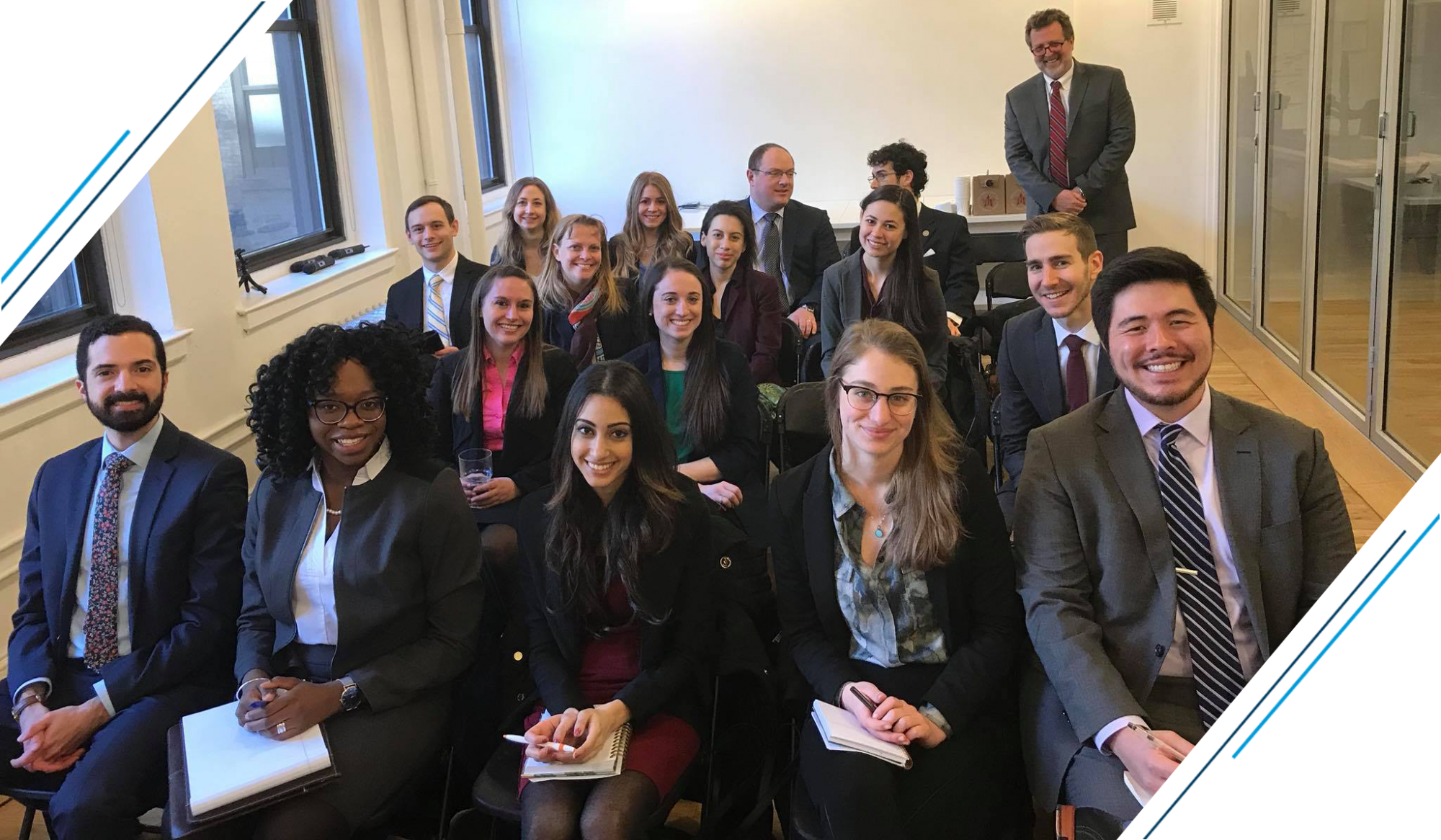 photo: a group of students and employers dressed in business suits are seated and smiling at the camera