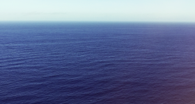Open ocean beneath blue sky.